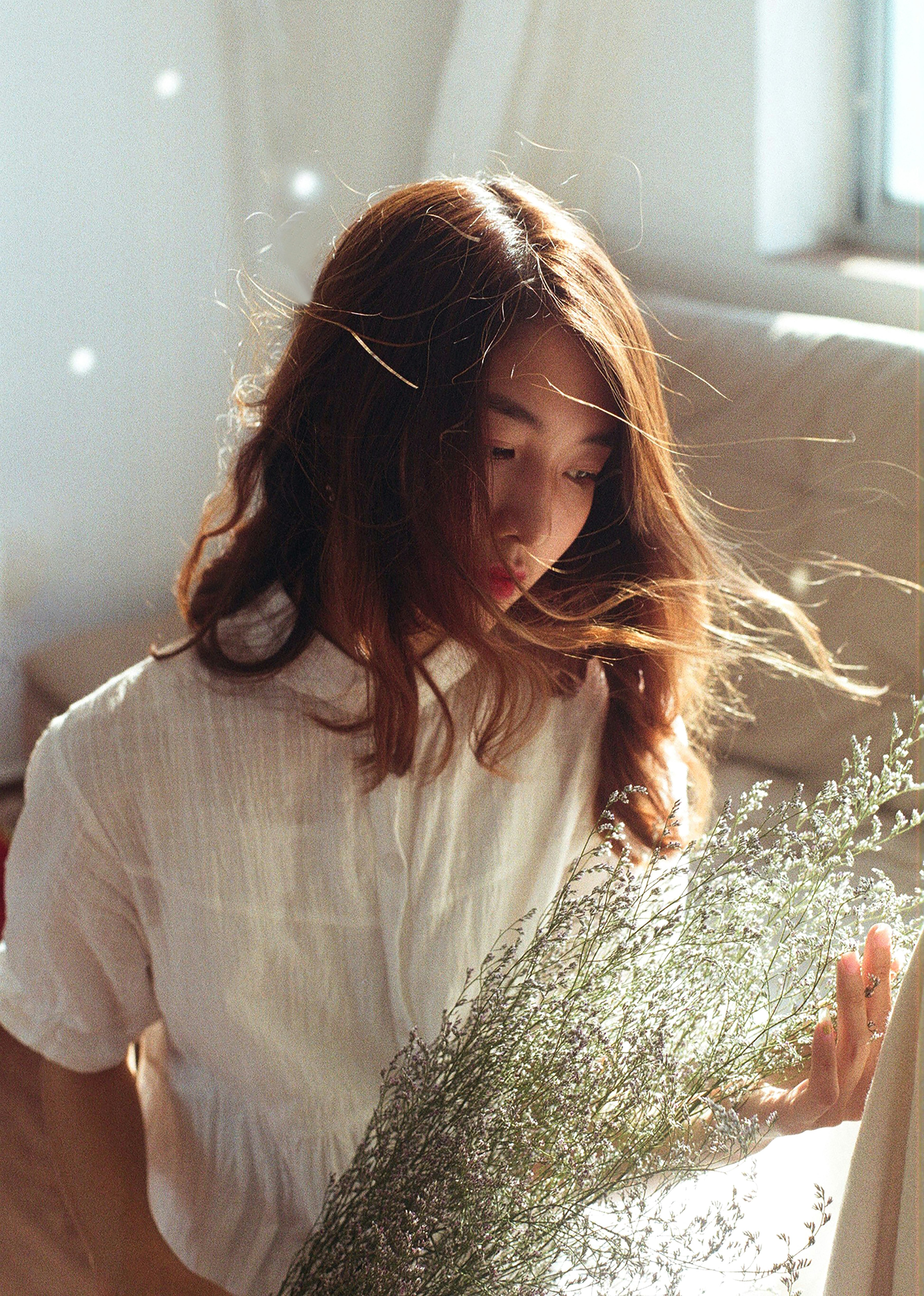 woman in white shirt holding green plant